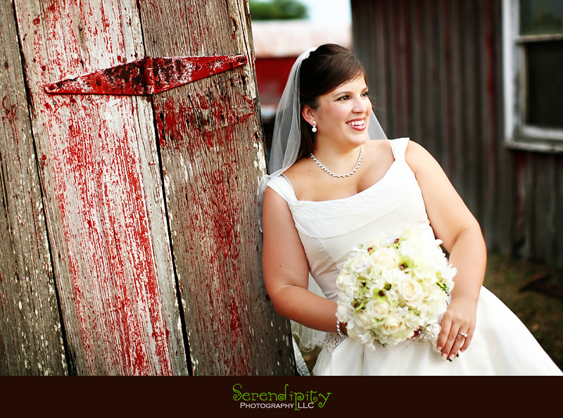 bride leaning against barn